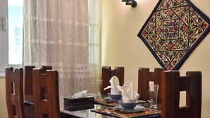 A dining table set with plates, bowls, and napkins, surrounded by wooden chairs. - Charming Downtown Apartment in the heart of Cairo (cairo)