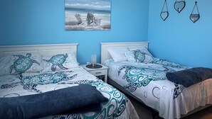 A room with two beds, a nightstand, a painting of a beach scene, and three heart-shaped wall decorations. - Excellent location! Close to Famous Boardwalk. One block from the boardwalk. (Wildwood)