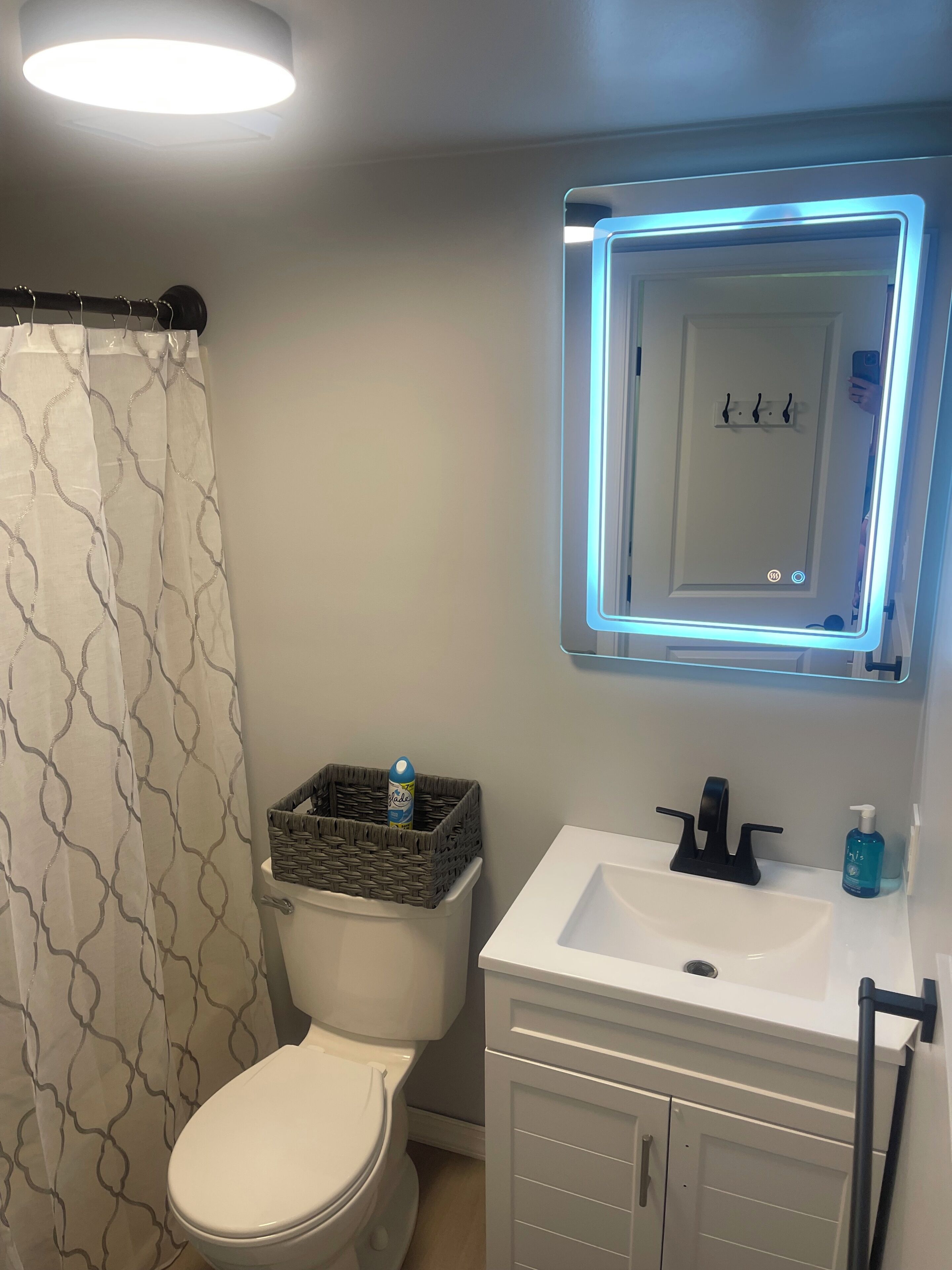 Un bagno con il water, un lavandino bianco con specchio e una tenda da doccia.