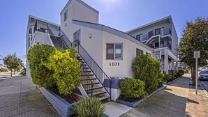 A modern building with a staircase leading to the entrance, number 3201, and a sign indicating it's a condo. - Excellent location! Close to Famous Boardwalk. One block from the boardwalk. (Wildwood)