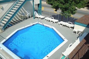 A rooftop pool with a clear blue pool, white lounge chairs, and a staircase leading to an upper level. - Excellent location! Close to Famous Boardwalk. One block from the boardwalk. (Wildwood)