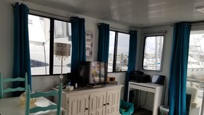 A compact living space with a kitchenette, a dining area, and a view of the outside. - Charlestown Houseboat Walk to attractions Be rocked to sleep (Boston)