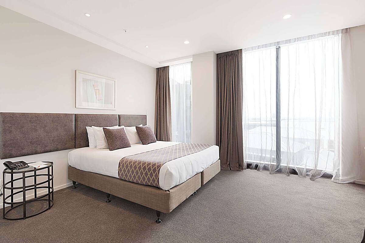 Habitación de hotel con una cama grande, un teléfono junto a la cama y un cuadro en la pared.