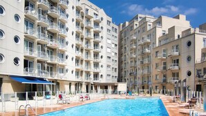 A modern apartment building with a swimming pool, balconies, and a covered outdoor seating area. - Residentie Zeezicht, Ref 104 (Oostende)