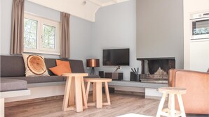 Un salon moderne avec un canapé gris, une table basse en bois, un téléviseur et une cheminée.