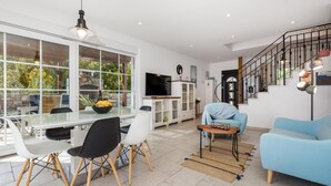 A modern living room with a dining area, a staircase, and large windows. - Beautiful home in Kornic (Kornic)