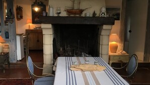 Comedor con chimenea, una mesa dispuesta para cuatro comensales y un techo de madera rústica.