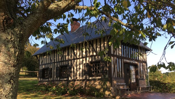 Un edificio de estilo Tudor con techo a dos aguas pronunciado, estructura de madera a la vista y una chimenea de ladrillo.
