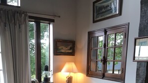 Una habitación acogedora con una mesa de madera, una silla azul, un sofá con cojines antiguos y una lámpara.