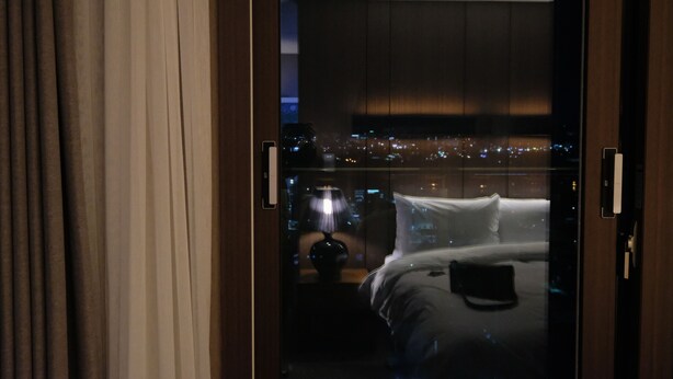 A hotel room with a bed, a nightstand, and a lamp. - New Raon Stay (Jinju)