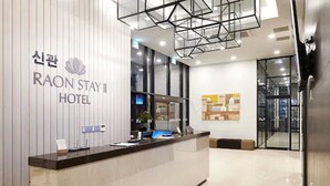 A modern hotel reception area with a reception desk, a digital screen, and a glass door entrance. - New Raon Stay (Jinju)
