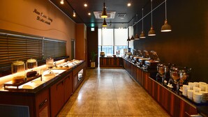 A buffet setup in a restaurant with a long counter, food dispensers, and a sign on the wall. - New Raon Stay (Jinju)