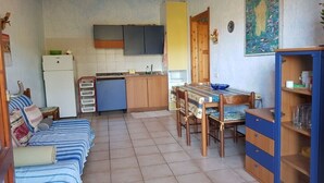 Een knus woongedeelte met een kitchenette, een eethoek en een bank.