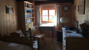 A cozy room with a wooden interior, a bookshelf, a desk with a computer, a chair, and a bed.