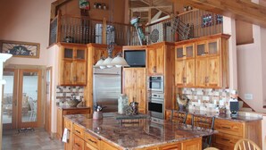 A spacious kitchen with wooden cabinets, granite countertops, and a stainless steel refrigerator.