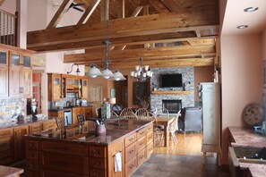 Une cuisine spacieuse avec des meubles en bois, un grand îlot central et une cheminée en pierre.