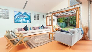 Una sala moderna con un sofá, una mesa de centro y una mesa de comedor. Hay un ventanal con vistas al exterior.