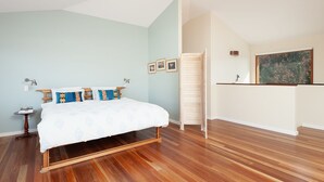 Un dormitorio con cama, piso de madera, paredes azul claro y una mesita de noche con lámpara.