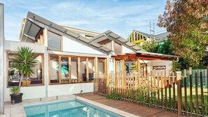 Una casa moderna con piscina, ventanas amplias y terraza de madera.