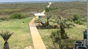 Un sentiero conduce a una piccola costruzione con un'insegna, immersa nel verde e con vista sull'oceano.