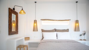 A bedroom with a bed, two bedside tables, a wooden stool, and two wall-mounted lamps. - VILLA AGAPITOS (naxos)