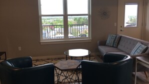 A living room with a large window, a gray sofa, two black chairs, and a small round table. - 2 bedroom + 1 bath apartment with amazing views! (Missoula)