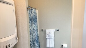 A compact bathroom with a washing machine, a shower curtain, a towel rack, and a toilet. - 2 bedroom + 1 bath apartment with amazing views! (Missoula)