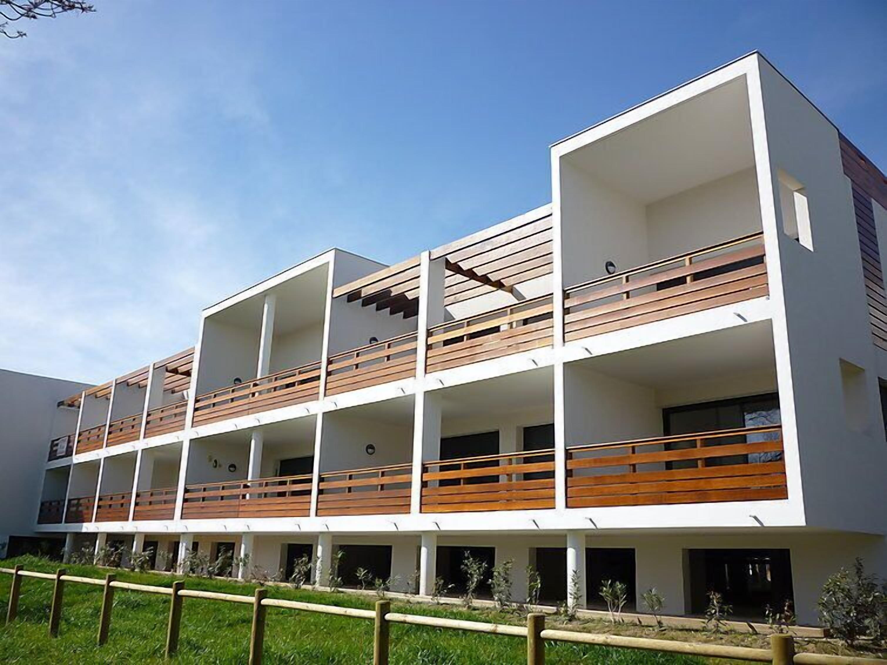 A modern multi-story building with balconies and a flat roof.