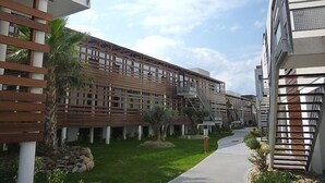 A modern building with a wooden facade, a central pathway, and a clear sky.