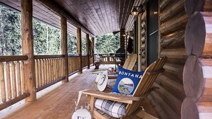 En veranda av trä med en trästol och en rutig filt, ett bord med en hatt och en kudde med texten ”MONTANA”, och en amerikansk flagga.