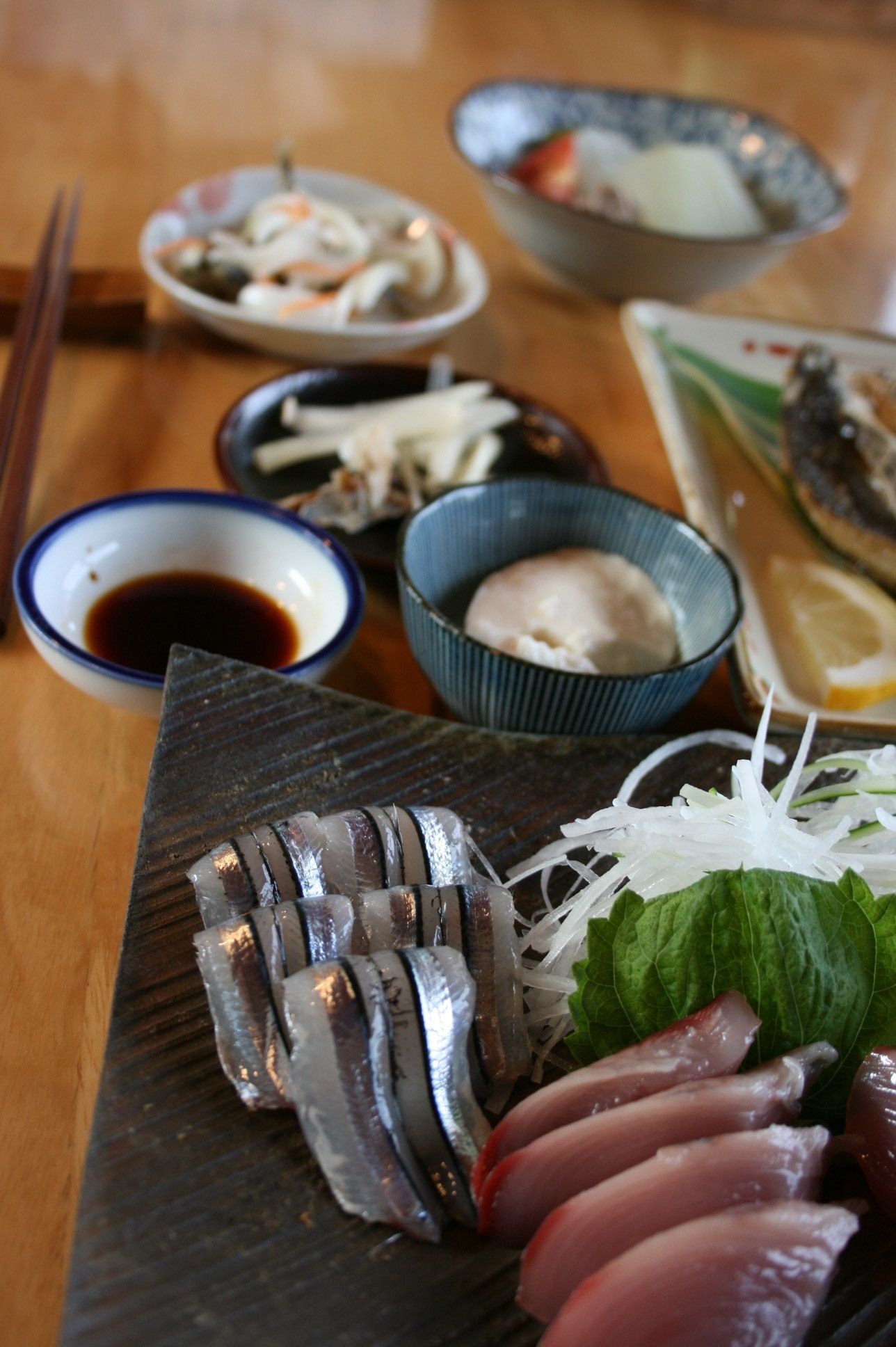 A variety of sushi dishes on a wooden table, including sashimi and nigiri.