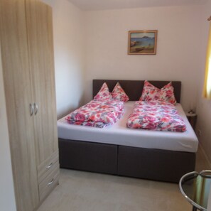 A bedroom with a bed, a nightstand, a wardrobe, and a painting on the wall. - Vacation apartment Untersberg 38sqm (Berchtesgaden)
