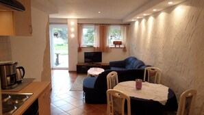 A compact living space with a kitchenette, a sofa, a television, and a dining area. - Vacation apartment Untersberg 38sqm (Berchtesgaden)