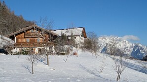 A wooden chalet with a sloped roof, surrounded by snow-covered trees and mountains. - Vacation apartment Untersberg 38sqm (Berchtesgaden)