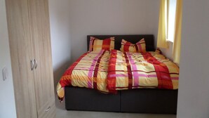 A bedroom with a bed, a wardrobe, and a window with curtains. - Vacation apartment Untersberg 38sqm (Berchtesgaden)