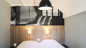 Ein Schlafzimmer mit einem Bett, zwei Wandleuchten, einer Uhr und einem großen Schwarzweiß-Wandbild.