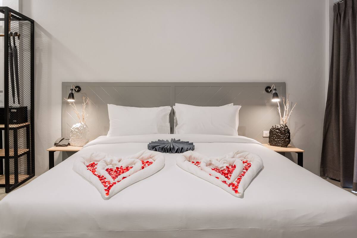 A neatly made bed with heart-shaped pillows and a small gift box.
