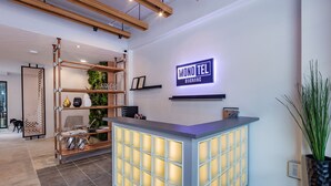 A reception desk with a modern design, a sign reading "MONO TEL @AONANG", and a plant to the right. - Monotel Aonang (Krabi)