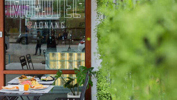 A restaurant with a glass window displaying the name "MOHOTEL @ AONANG". - Monotel Aonang (Krabi)