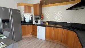 Une cuisine moderne avec des meubles en bois, un four encastré, un four à micro-ondes et un lave-vaisselle.