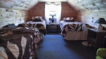 Ein kleines, gemütliches Schlafzimmer im Dachgeschoss mit zwei Betten, einem Nachttisch und einer Lampe.
