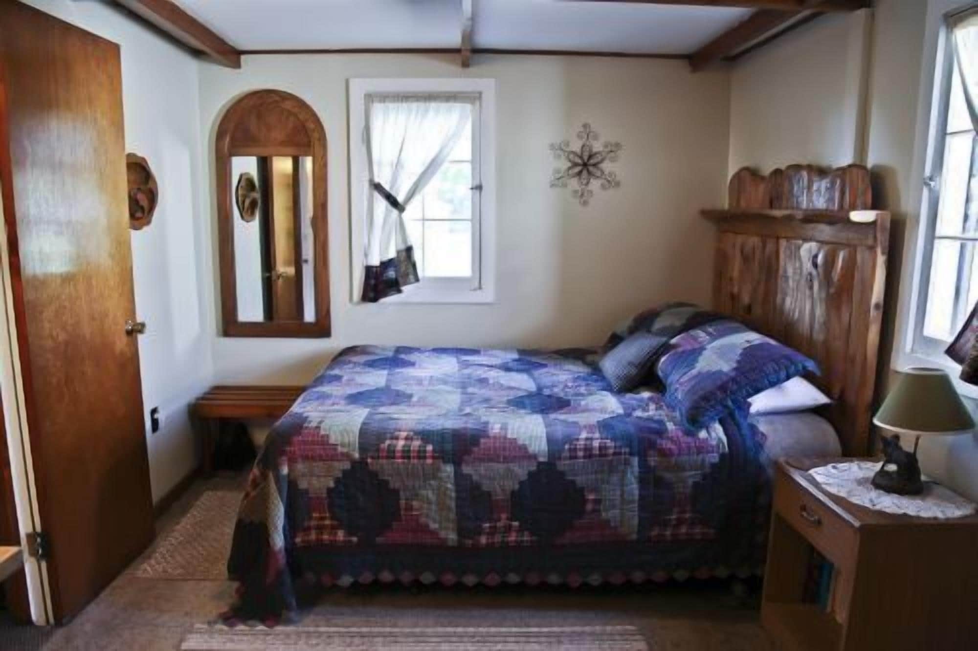 Un dormitorio con una cama grande, un armario de madera, un espejo y una ventana con cortinas.