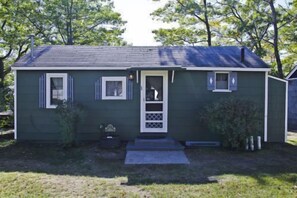 A single-story house with a front door, two windows, and a small porch. - #1 - Cedar Village 2 Bedroom Cabin by RedAwning (Carp Lake)