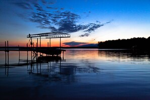A calm lake at sunset with a dock and a covered seating area. - #8 - Mackinac Point 1 Bedroom Cabin by RedAwning (Carp Lake)