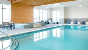 Una piscina con techo de madera, escalones azulejados y sillas de descanso.