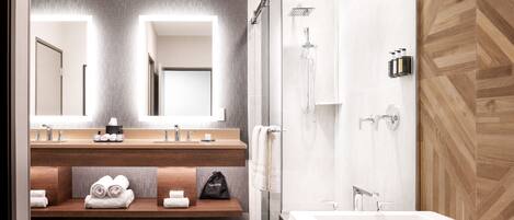 A modern bathroom with a large mirror, two sinks, a shower, and a bathtub.