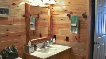 A wooden cabin bathroom with a wooden vanity, a sink, a toilet, and a mirror.