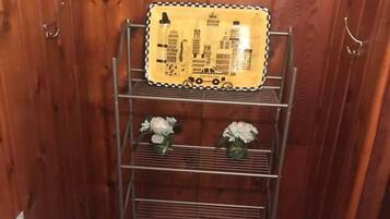 A compact bathroom with a toilet, a metal shelf unit with a cityscape design, and a trash bin.
