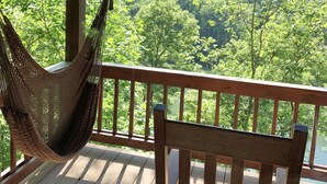 A wooden deck with a hammock and a chair, overlooking a forested landscape. - Lake Hideaway 2 - Lakeside Log Cabin, Fishing Boat, Private Dock & Mountain View (Cherry Log)