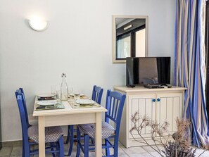 Ein Essbereich mit Tisch, Stühlen, einem Fernseher und einem Schrank.